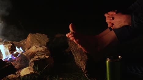 la hembra se brilla con los pies y baila con los dedos cerca de una fogata en la noche.