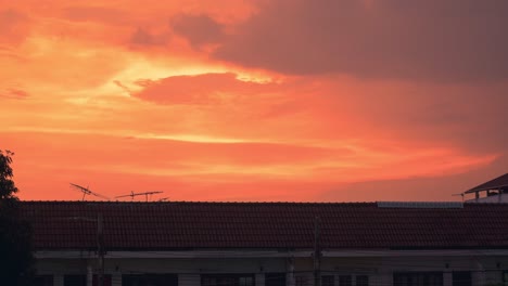 colorful sunset over roof of houses with antenna. - wide static
