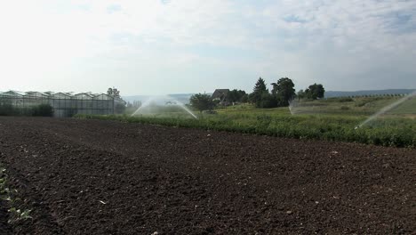 campo y casa verde en baviera con riego por aspersión, alemania