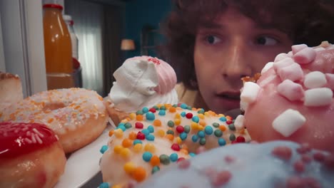 close-up view of a teenager looking at various donuts and pastries in a refrigerator