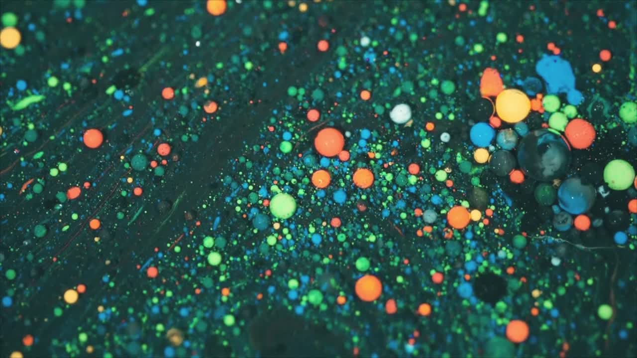 Gouttelettes vives et colorées se déplaçant et se mélangeant dans un liquide abstrait