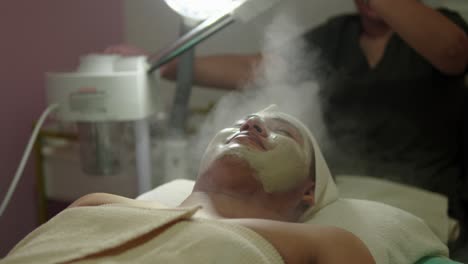 chico latino mexicano hombre cliente disfrazado sonrisa y disfrutar spa día centro de bienestar tratamiento terapéutico con vapor máquina caliente piel facial