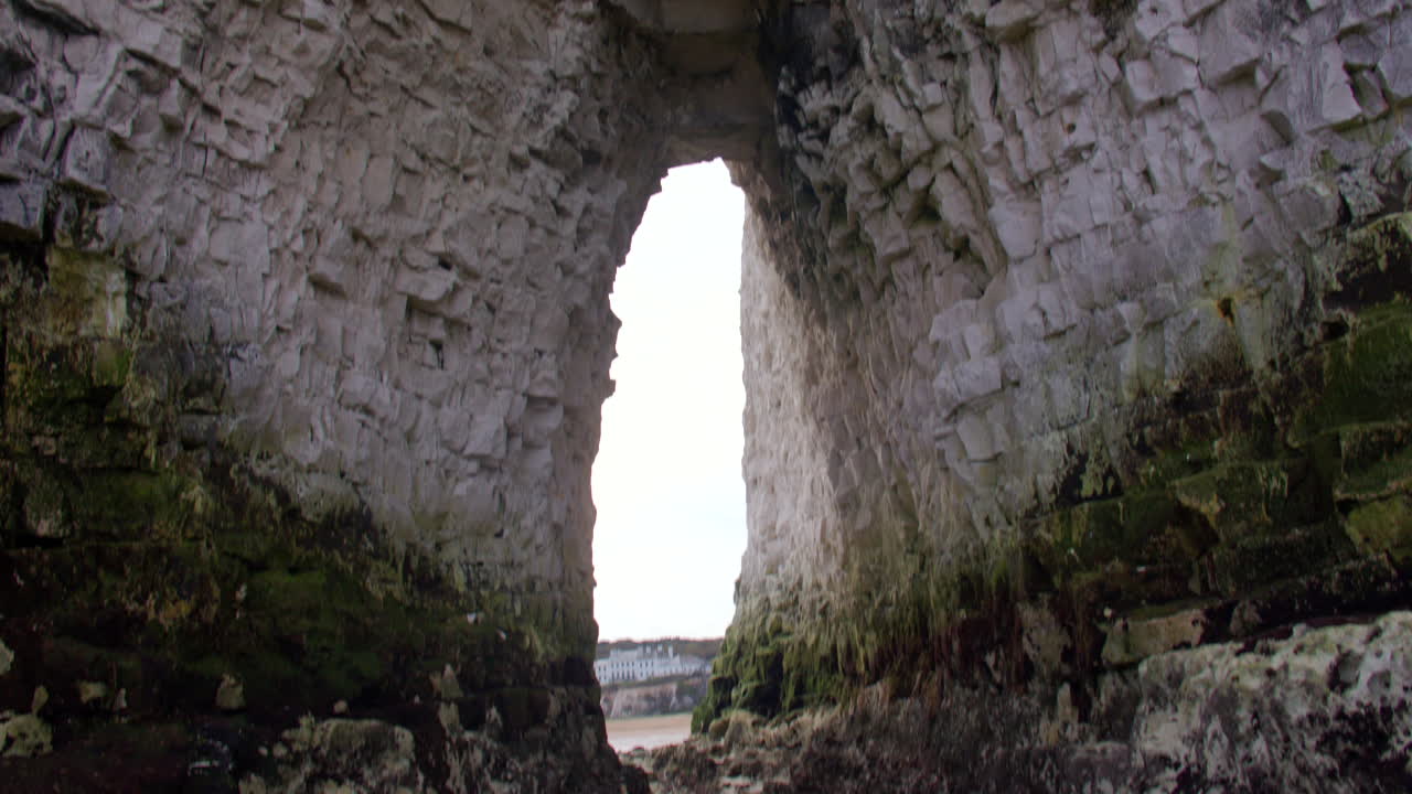 Mid shot Tilting down looking though the Kingsgate Arch chalk stack with Kingsgate bay in background