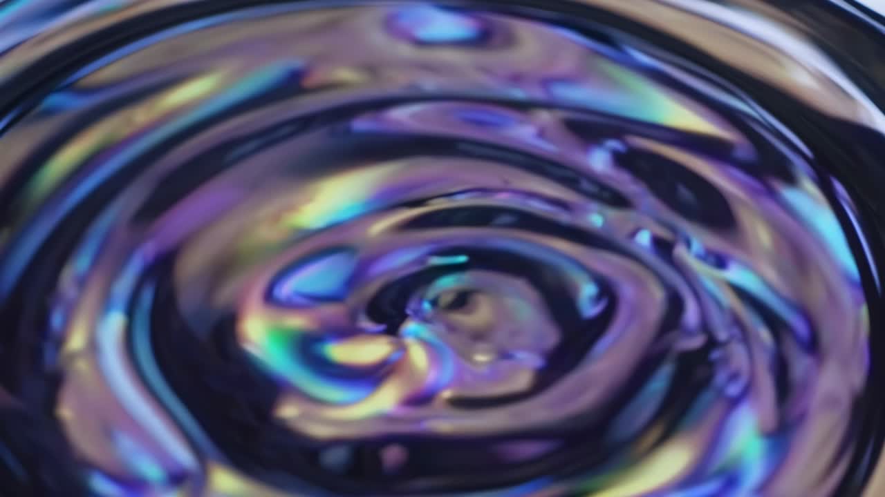 Abstract video of swirling iridescent liquid with a top-down camera angle, showcasing vibrant colors