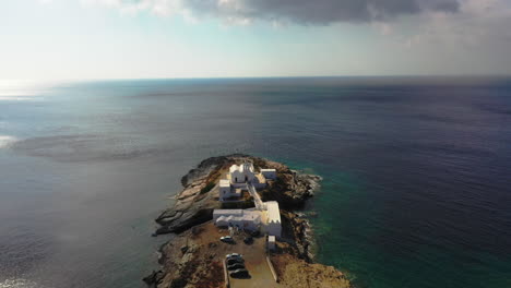 aerial shot descending and approaching the church of chrisopigi on the cycladic island of sifnos, greece.