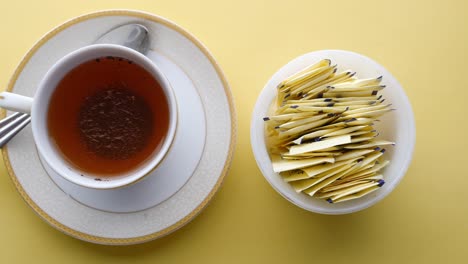 sugar substitute sweetener packet and tea cup on yellow background ,