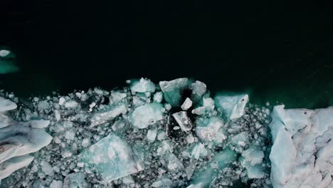 aerial top down, melted ice chunks in dark cold glacial lake jokulsarlon iceland