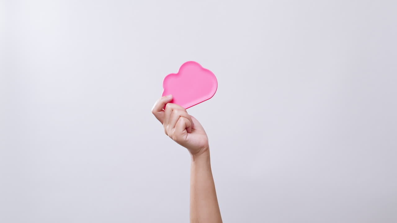 여자의 손은 복사 공간이 있는 흰색 스튜디오 배경에 구름 아이콘 색상 분홍색 기호를 보여줍니다.