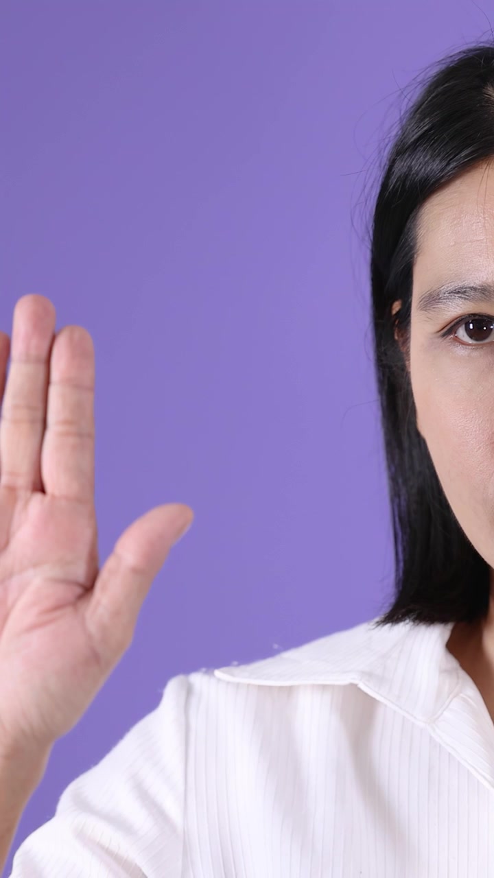 Asian Woman Making a Stop Gesture Against a Purple Background
