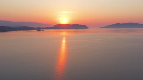 an aerial view of a sunrise on the horizon, over the aegean sea, with a few islands in the background