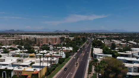 drone footage over residential area and busy road in scottsdale, arizona with camelback mountain in the background