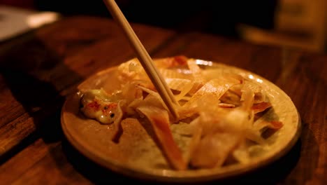 chopsticks interacting with grilled skate fin dish