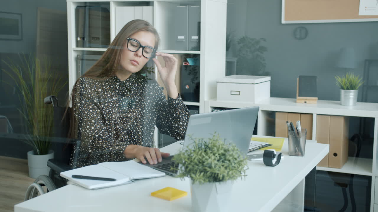 Donna in sedia a rotelle che lavora a una scrivania in un ufficio