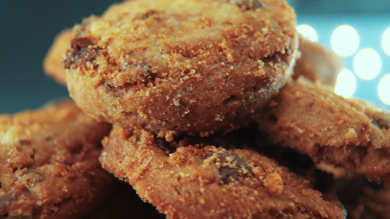 una toma cinematográfica macro de un plato lleno de galletas de chocolate crujientes y jugosas, en un soporte giratorio, iluminación de estudio, cámara lenta, movimiento suave, video 4k