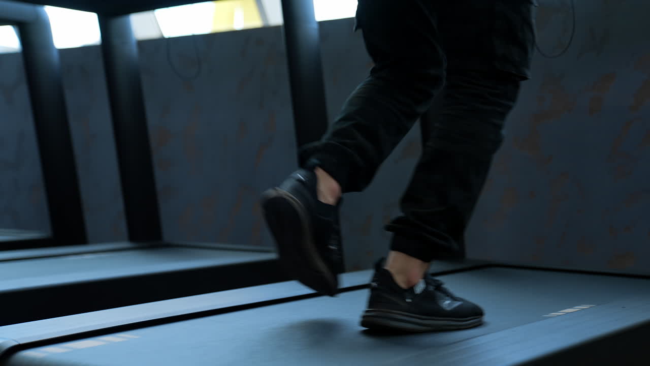 Male training in sport club. Close up of athletic feet running on treadmill in fitness gym