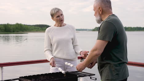 un par de personas mayores asando malvaviscos en una barbacoa 1