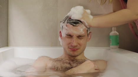hombre tomando un champú en la bañera
