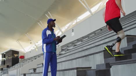 Diverse-male-coach-and-disabled-athlete-with-prosthetic-leg-training,-running-up-stairs