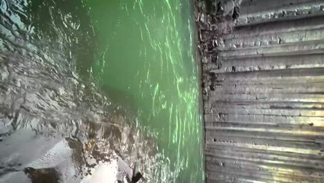 Emerald-green-water-flowing-down-the-Studlagil-Canyon-in-Iceland-slow-motion-panning-to-the-exit-and-with-blue-skies