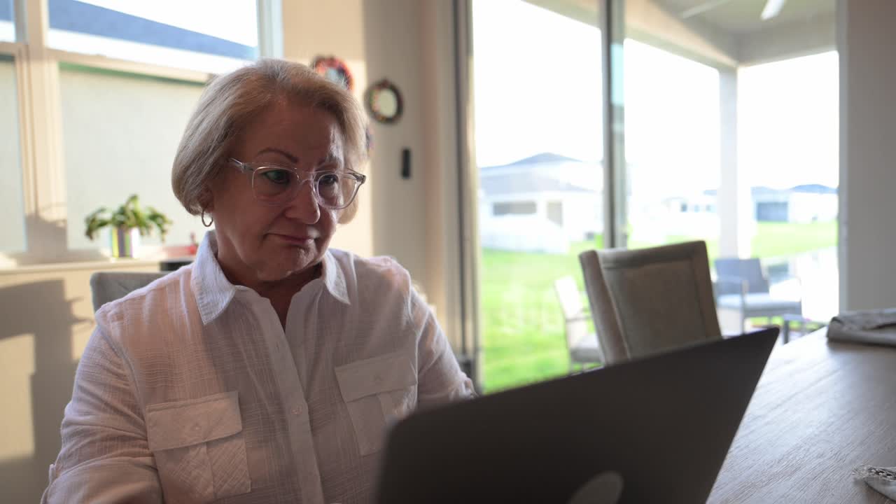 senior citizen woman stares at the computer screen in disbelief after reading an election news article