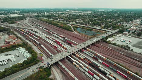 high-angle-of-trains-with-freight,-overpass-with-commuting-cars