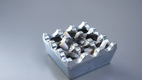 used metal ashtray with cigarette butts