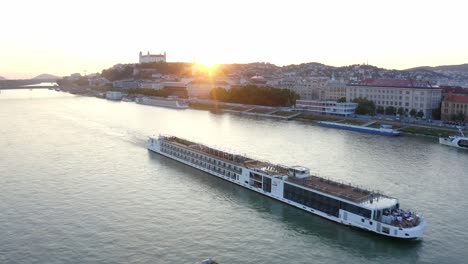 small boat and a large ship meet on danube river in bratislava at sunset