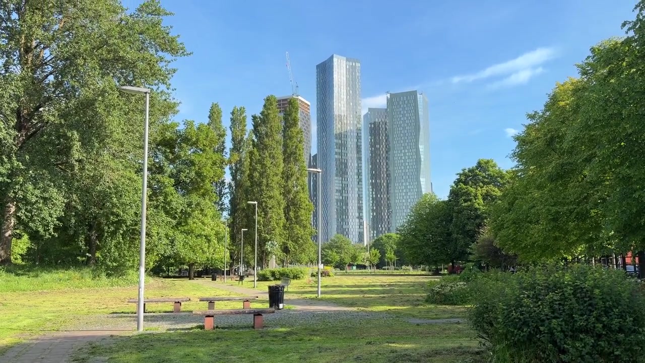 イギリス、マンチェスターの公園からの眺め。近代的な高層ビルと緑豊かな木々。