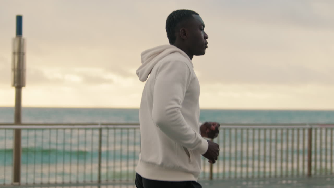 Giovane uomo di colore che fa jogging lungo il lungomare