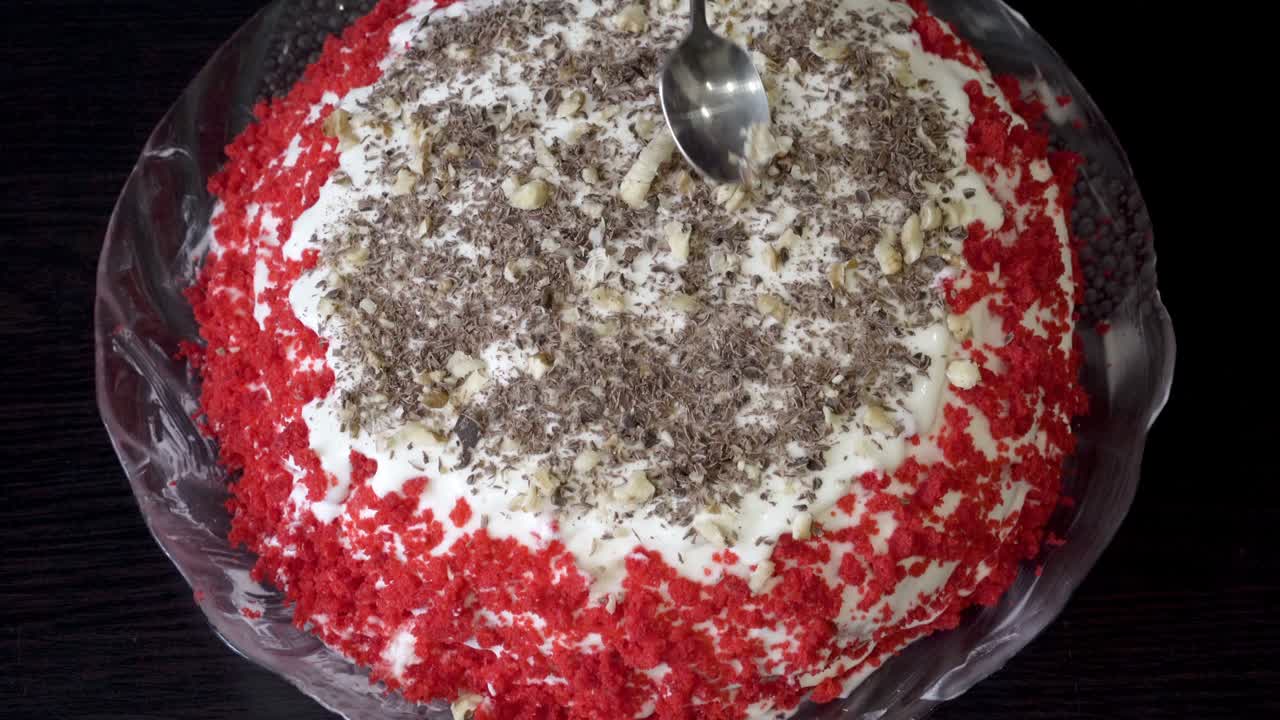 페이스트리 셰프는 아름다운 케이크를 준비하고 은 견과류와 초콜릿을 뿌립니다. 검은 테이블에 은 케이크. 개념. 격리 기간 동안 소규모 사업. 근접. 상단 뷰. 얼굴없는. 4k.