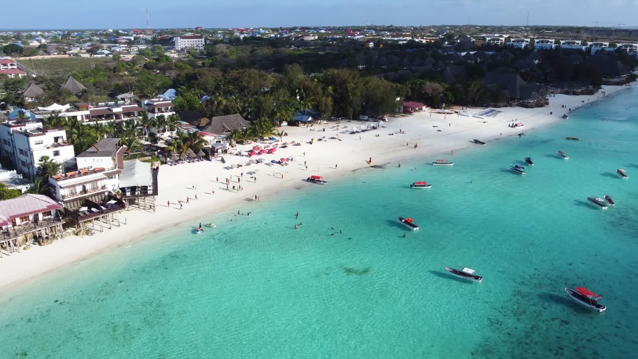 una impresionante vista aérea de la playa de nungwi y la ciudad de nungwi con muchas actividades acuáticas y de playa en el océano, incluidos muchos barcos