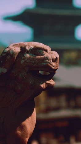 a closeup of a stone lion statue in front of a japanese temple