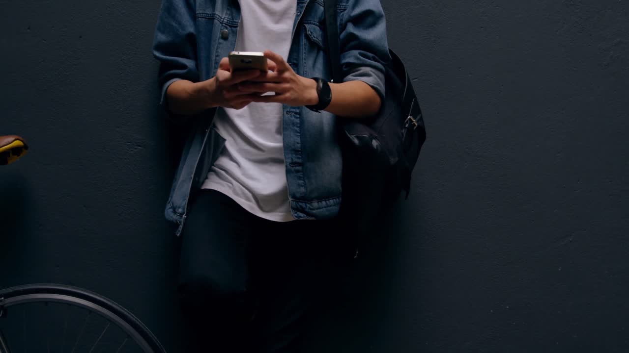 Uomo che usa il cellulare appoggiato al muro 4k