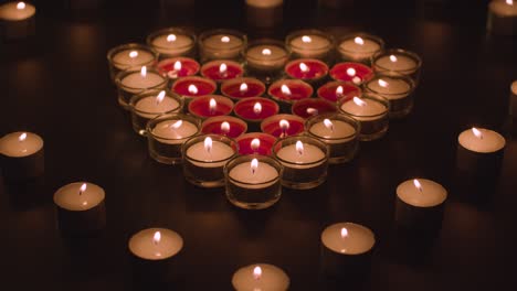 romantic red and white candles in the shape of a heart on black background