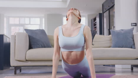 Mujer-Vestida-De-Fitness-En-Casa-En-El-Salón-Haciendo-Estiramientos-Y-Haciendo-Ejercicio-En-La-Colchoneta,-Filmada-En-Cámara-Lenta