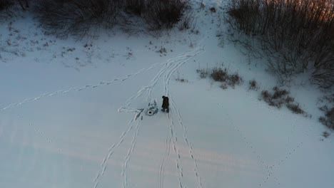 vista aérea de una persona patinando sobre hielo en un estanque congelado y alcanzando un pequeño agujero de pesca