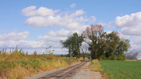 antique steam engine with passenger cars approches stright on view on a sunny autumn day