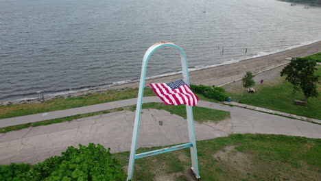 aerial orbit of arch with american flag in the wind, rocky point ri