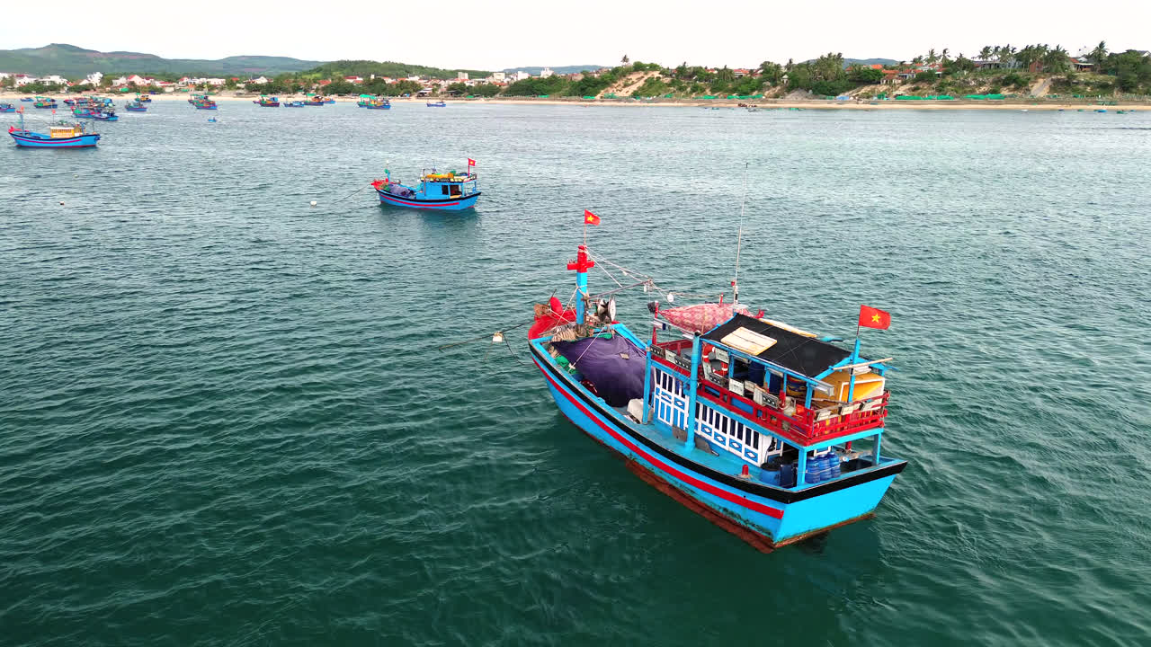 Colorful fishing boats anchored in turquoise waters off Vietnam coast with flags waving in wind