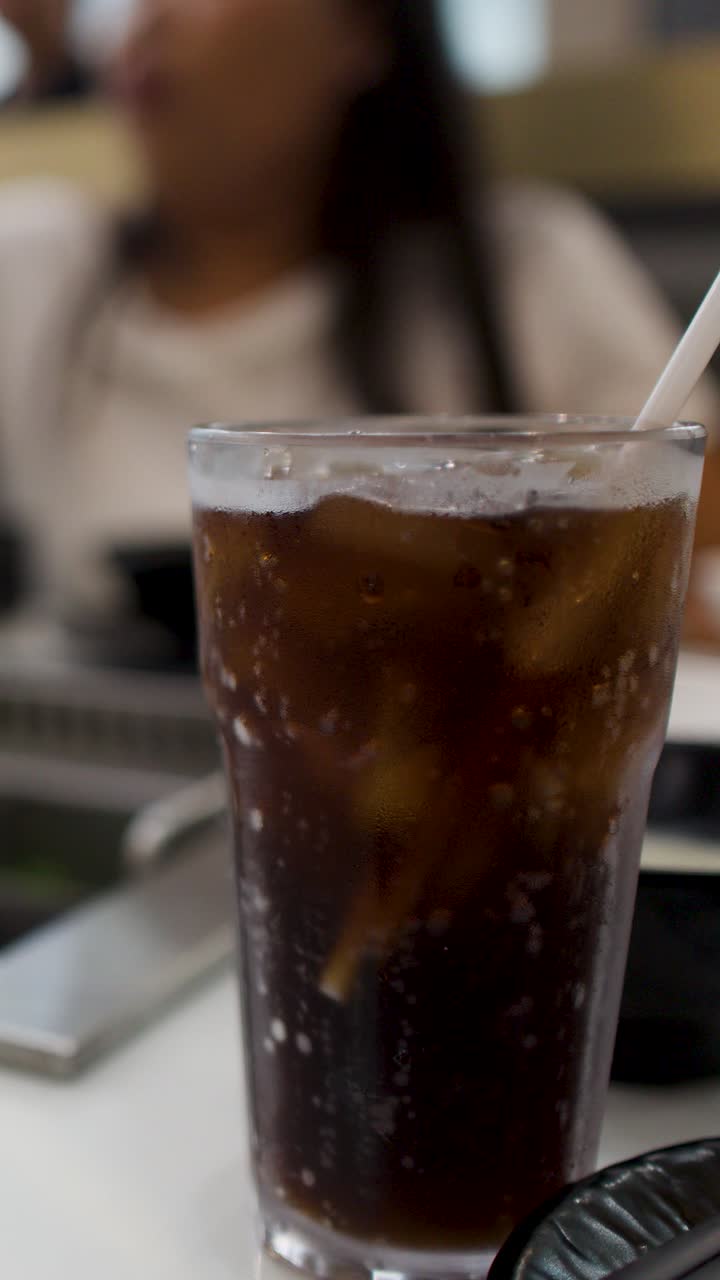 Un bicchiere di cola fredda con ghiaccio è su un tavolo durante una cena barbecue.