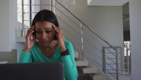 stressed african american woman using laptop while working from home