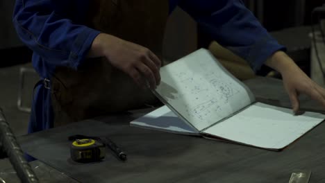 faceless mechanic flipping notebook in workshop