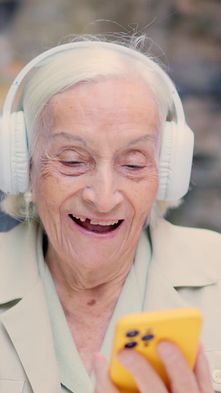 Elderly woman with headphones using a mobile phone