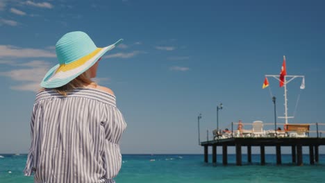a woman admires the beautiful sea, rear view. it stands near the pier with a raised turkish flag. rest in turkey concept
