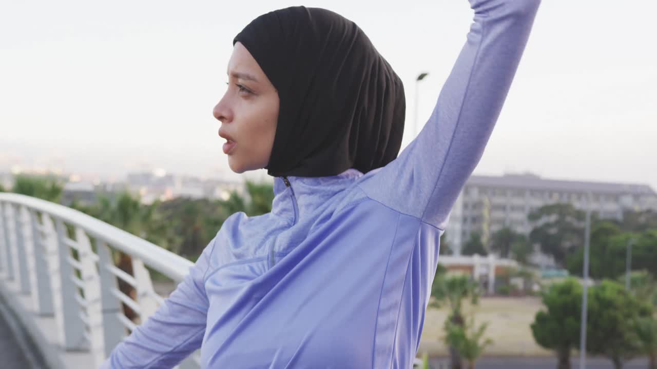 Woman wearing hijab stretching outside