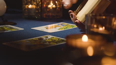 Close-Up-Of-Woman-Giving-Tarot-Card-Reading-On-Candlelit-Table-Holding-The-Lovers-Card-2