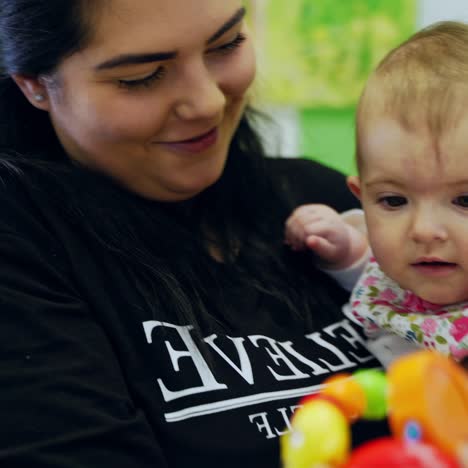 experienced pediatrician showing toy to baby. young woman pediatrician and cute little kid girl