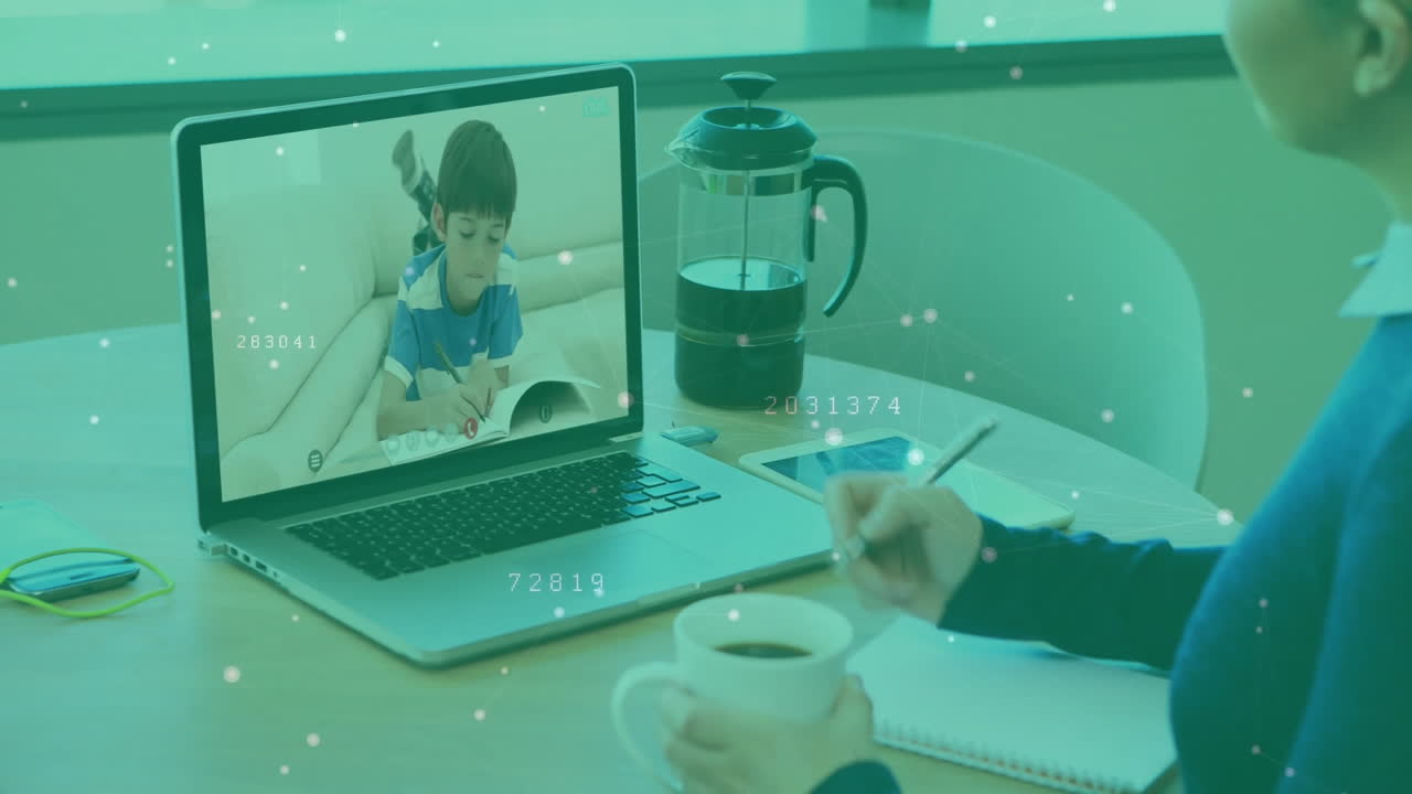 woman writing notes during remote learning session, showing laptop, coffee, floating data overlays