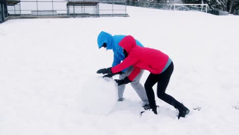 couple pushing a huge snowball