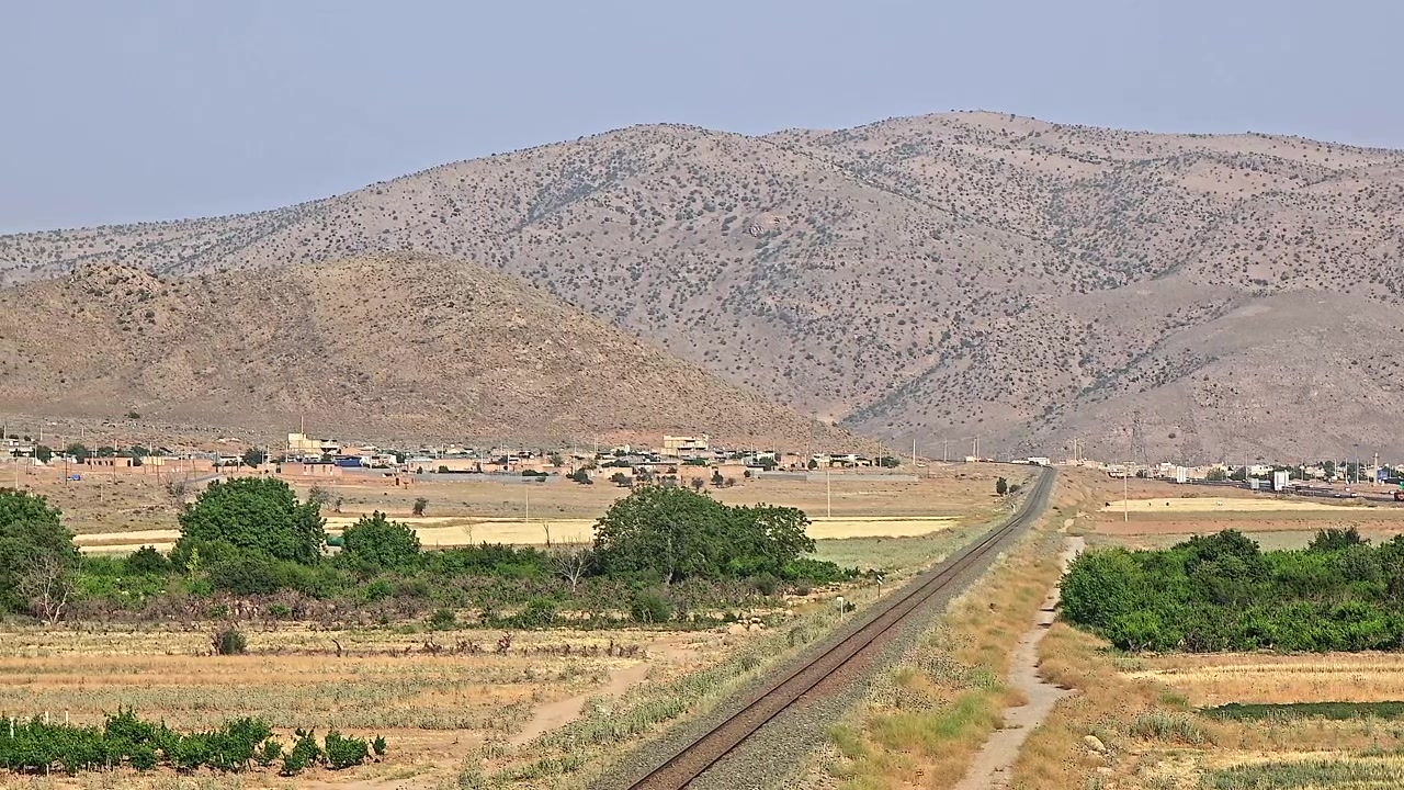 Paesaggio panoramico con binari ferroviari e un lontano villaggio di montagna